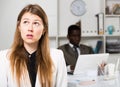 Upset woman and man colleague working with laptop on background in office Royalty Free Stock Photo