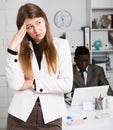 Upset woman and man colleague working with laptop on background in office Royalty Free Stock Photo