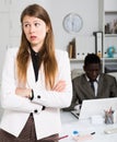 Upset woman and man colleague working with laptop on background in office Royalty Free Stock Photo