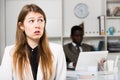 Upset woman and man colleague working with laptop on background in office Royalty Free Stock Photo