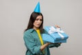 Upset woman opening birthday gift box and looking inside with disappointed expression.