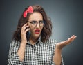 Upset woman on the phone over dark gray - black background. Annoyed girl talking