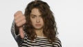 Upset woman showing thumbs down in studio. Unhappy girl showing dislike gesture Royalty Free Stock Photo