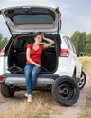 Upset woman sitting open car trunk and waiting for help to chang Royalty Free Stock Photo