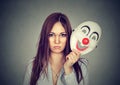 Upset worried woman with sad expression taking off clown mask