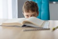 Upset 8 years old boy doing his homework at the table