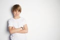 Upset young boy in white T-shirt posing in front of white empty wall. Portrait of fashionable male child. Smiling boy Royalty Free Stock Photo