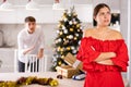 Upset young couple arguing among themselves before X-mas Eve near Christmas tree in kitchen at home Royalty Free Stock Photo