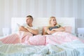 Upset young couple having marital problems or a disagreement sitting side by side in bed facing in opposite directions Royalty Free Stock Photo