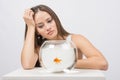 Upset young girl looking at goldfish in a fishbowl Royalty Free Stock Photo