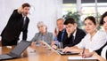 Upset young girl sitting with colleagues scolded by angry boss