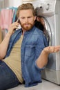 upset young husband on phone doing laundry