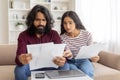 Upset young indian couple checking bills, sitting on couch Royalty Free Stock Photo