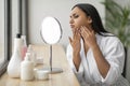 Upset young indian woman looking at mirror, touching her face Royalty Free Stock Photo