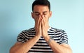 Upset young man cover his face with hands, posing against white blue wall. Sad male feels worried. Negative emotions Royalty Free Stock Photo