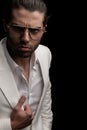 upset young man with glasses holding white suit and frowning Royalty Free Stock Photo