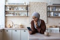 Upset young muslim woman in hijab at home in kitchen looking at phone, checking account, received message, worried Royalty Free Stock Photo