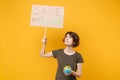 Upset young protesting woman hold protest sign broadsheet placard on stick Earth world globe isolated on yellow