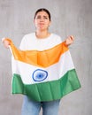 Upset young woman holding flag of India on gray wall background, sad expression Royalty Free Stock Photo