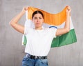 Upset young woman holding flag of India on gray wall background, sad expression Royalty Free Stock Photo