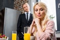 upset young woman looking down while husband in suit