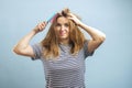 Upset young woman looking with shock at her damaged hair on blue background Royalty Free Stock Photo