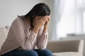 Upset biracial woman sit on couch feeling stressed at home