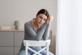 Upset young woman sits alone, looking away with sad expression at home interior Royalty Free Stock Photo