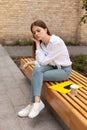 Upset young woman sits outdoors. Headache and burnout Royalty Free Stock Photo