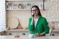 Upset young woman sitting at home in the kitchen with a mobile phone and crying. He looks sadly at the camera, wipes his Royalty Free Stock Photo