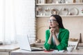 Upset young woman sitting at home with a laptop. She looks thoughtfully out the window Royalty Free Stock Photo