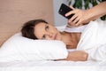 Upset young woman using phone in bed, looking at screen, insomnia