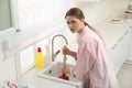 Upset woman using plunger to unclog sink drain in kitchen Royalty Free Stock Photo