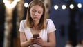 Upsetting news. Teen girl messaging with her phone in a cafe in Royalty Free Stock Photo