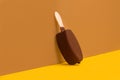 Chocolate dipped ice lolly on a brown and yellow background