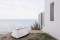 Upside down white boat on the beach, next to a white house and a green plant. Calm sea in the background. Altea Royalty Free Stock Photo