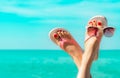 Upside woman feet and red pedicure wearing pink sandals, sunglasses at seaside. Funny and happy fashion young woman relax