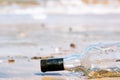 Upturned glass bottle buried in the sand with waves, surf and sand in the background at Diu beach Gujarat India