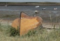 Upturned old orange coloured boat on the grass Royalty Free Stock Photo