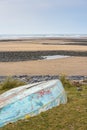 An upturned small boat washed up on the shoreline of a beautiful unspoiled beach Royalty Free Stock Photo