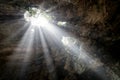 Upward shot of light rays entering a deep cave and illuminating the surrounding stone walls