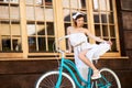 Upward shot of a pretty girl on a turquoise bike near a cafe Royalty Free Stock Photo