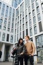 Upward shot of a young couple standing close in front of high storey building
