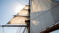 Upward view captures the towering white canvas sails and complex rigging of a historic tall ship silhouetted against the bright Royalty Free Stock Photo