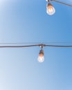 Upward view string wired Illuminated bulbs on clear blue sky background Royalty Free Stock Photo