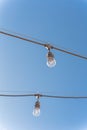 Upward view string wired Illuminated bulbs on clear blue sky background Royalty Free Stock Photo