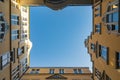 Upward view to blue sky framed in old tenement house walls like in well Royalty Free Stock Photo