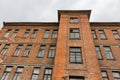 Upward view to old red brick wall building with windows and cloudy sky on the background Royalty Free Stock Photo