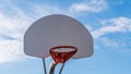 Upwards view of basketball hoop against a bright blue sky