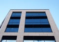 View of the facade of a modern office buildings with blue sky reflected in the rows of geometric windows Royalty Free Stock Photo